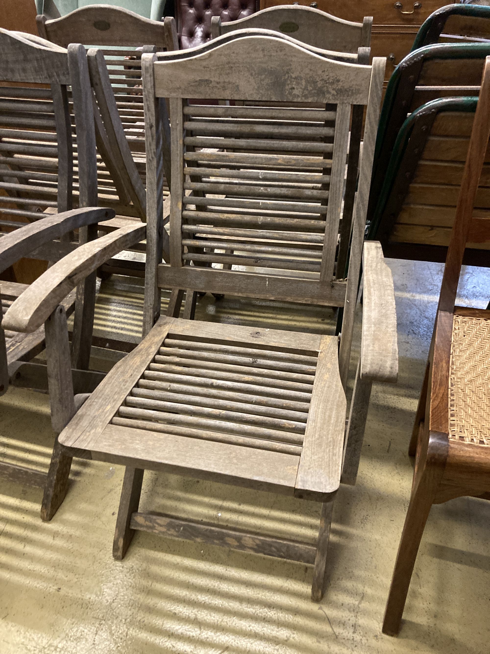 A set of six weathered teak folding garden chairs, two with arms